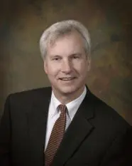 A man in suit and tie smiling for the camera.